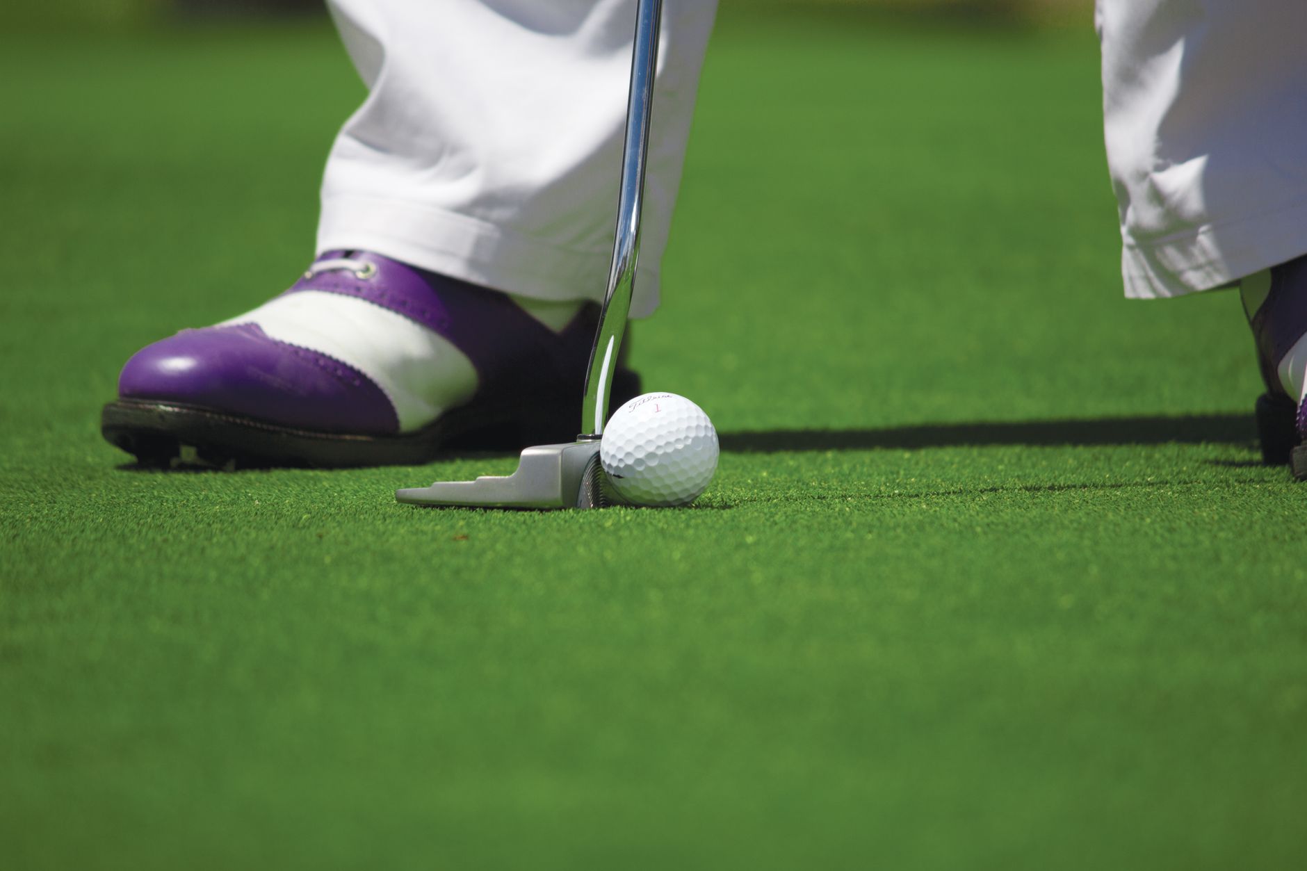 person in white pants playing golf